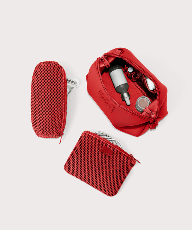 Dagne Dover Large Hunter Toiletry Bag in a fiery, saturated red leaning toward orange unzipped and seen from above with the removable air mesh pouch alongside it.