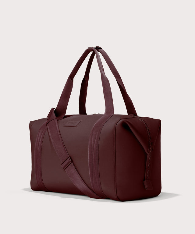 Dagne Dover Extra Large Landon Carryall in a deep brown with purple undertones seen from an angle.