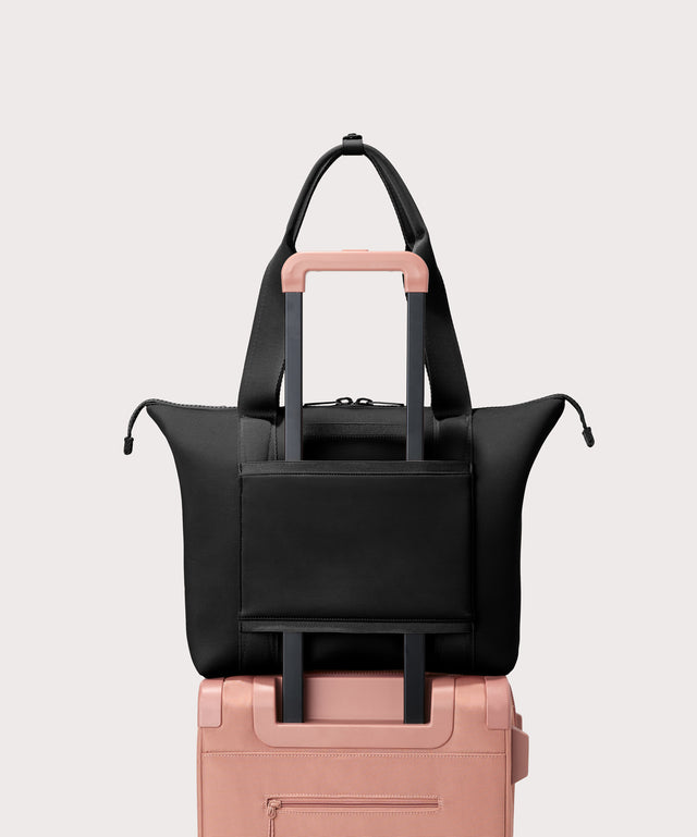 Tote  bag in a  black seen from the back view on suitcase.
