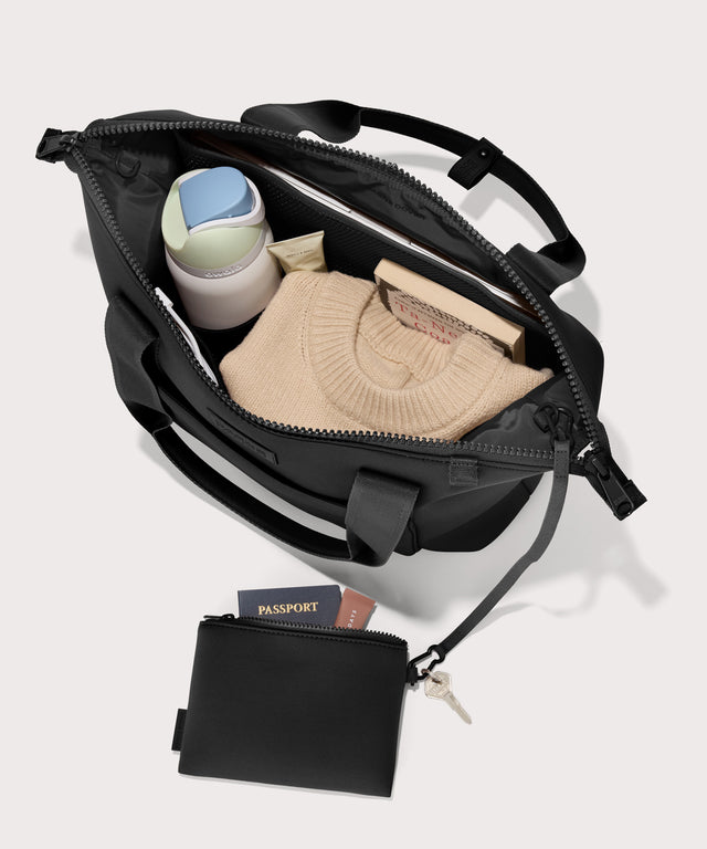 Tote  bag in a black seen from the top down view showing interior mesh pouch.
