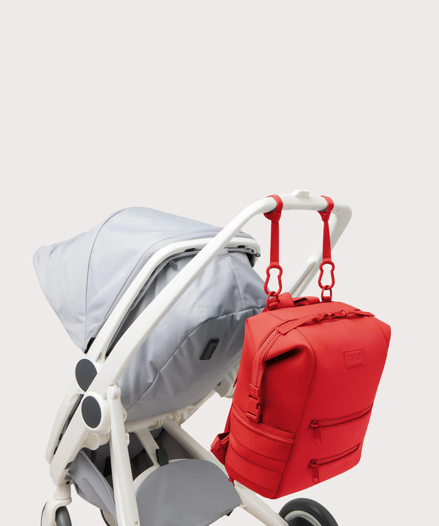 Dagne Dover Large Indi Diaper Backpack in a fiery, saturated red leaning toward orange attached to a stroller.