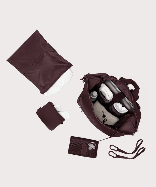 Dagne Dover Large Indi Diaper Backpack in a deep brown with purple undertones unzipped showing it's water resistant bag, interior pockets, and changing mat.