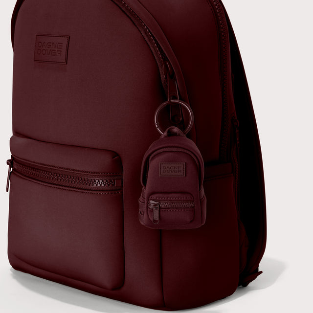 Dagne Dover Dakota Keychain in a deep brown with purple undertones clipped onto a backpack.
