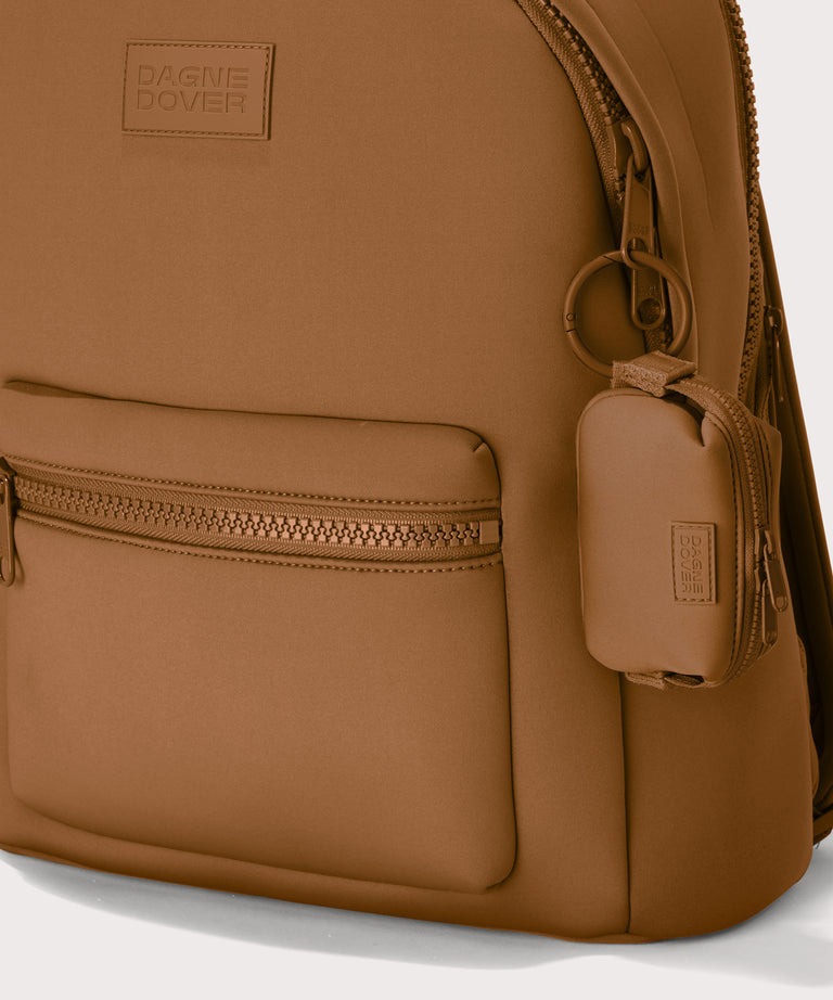 Hunter keychain in a saturated, warm medium-brown with burnt orange undertones . front angle showing keychain on a backpack. 