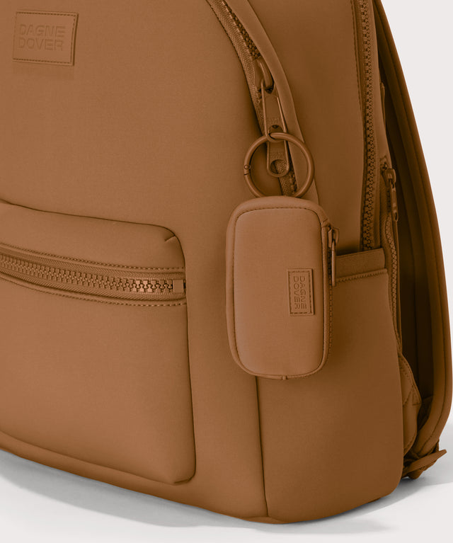 Mara Keychain in a saturated, warm medium-brown with burnt orange undertones. front angle showing keychain on a dakota backpack. 
