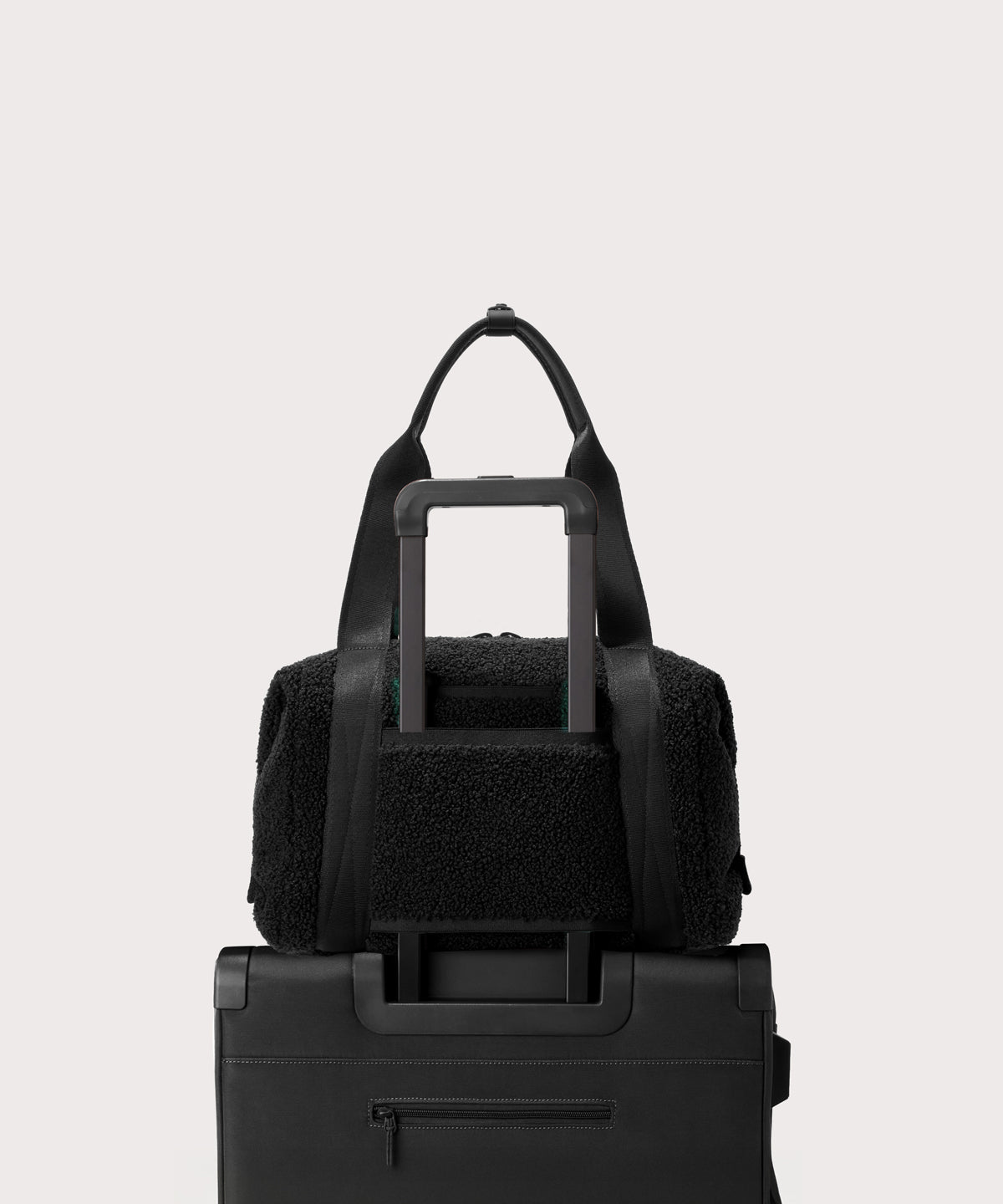 Medium landon carryall in a black.. displaying luggage sleeve.  In a  Faux Shearling  a soft, wool-like plush made with recycled materials.
