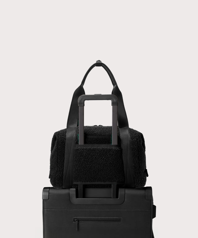 Medium landon carryall in a black.. displaying luggage sleeve.  In a  Faux Shearling  a soft, wool-like plush made with recycled materials.
