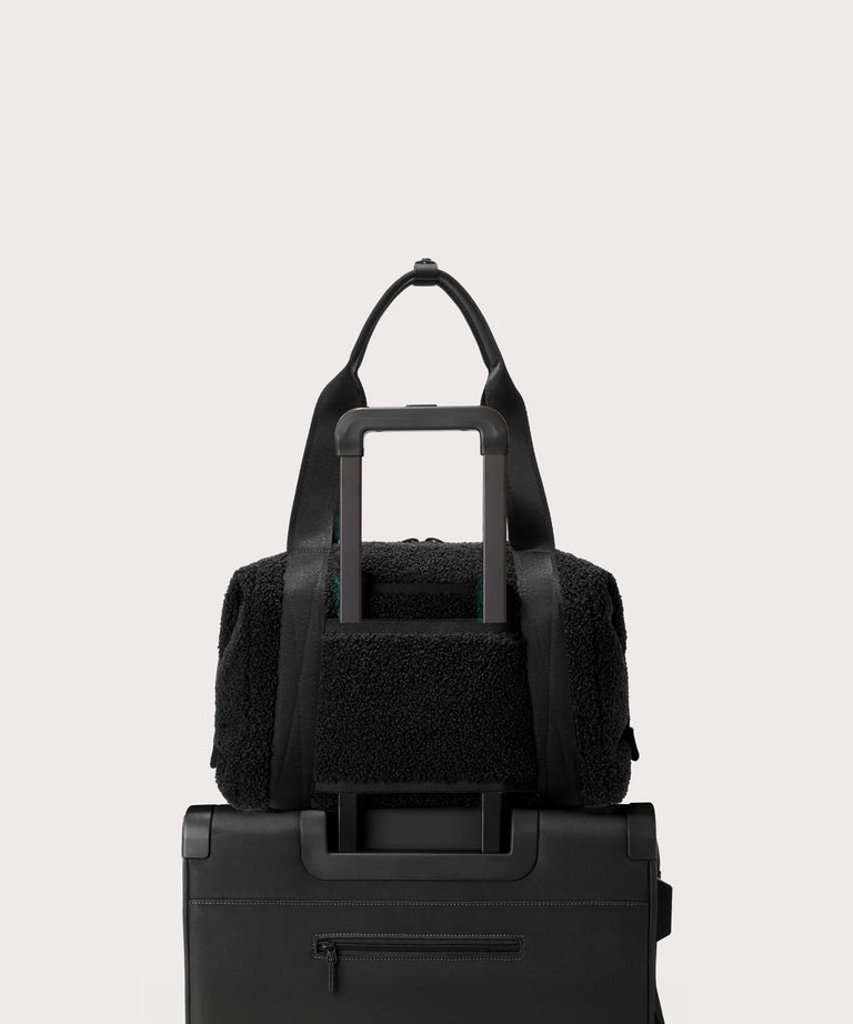 Medium landon carryall in a black.. displaying luggage sleeve.  In a  Faux Shearling  a soft, wool-like plush made with recycled materials.
