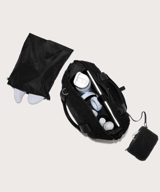 Medium landon carryall in a black. . unzipped, top down view.  In a  Faux Shearling  a soft, wool-like plush made with recycled materials
