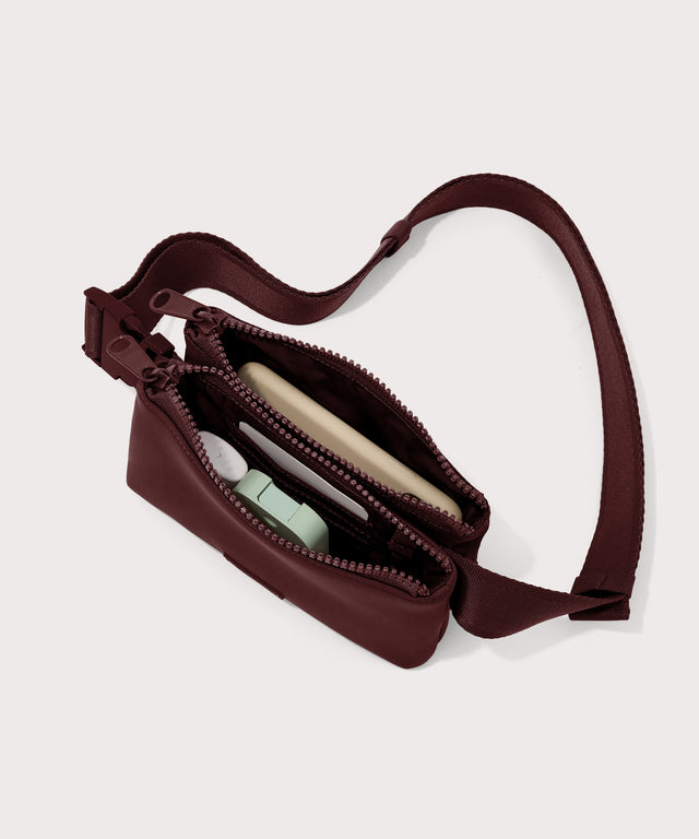 Dagne Dover Bennie Sling in a deep brown with purple undertones unzipped displaying interior of both pouches.
