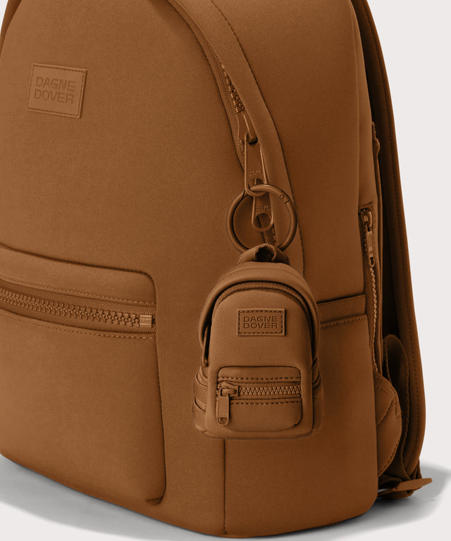 Dakota keychain in a saturated, warm medium-brown with burnt orange undertones front view on a dakota backpack. 

