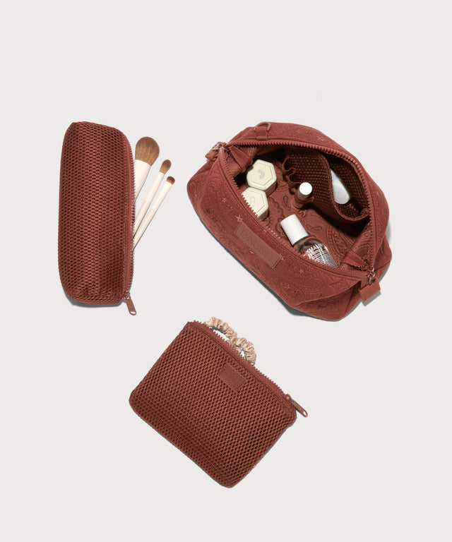 Dagne Dover Large Hunter Toiletry Bag in a rich, warm brown with an embroidered paisley print unzipped and seen from above with the removable air mesh pouch alongside it.