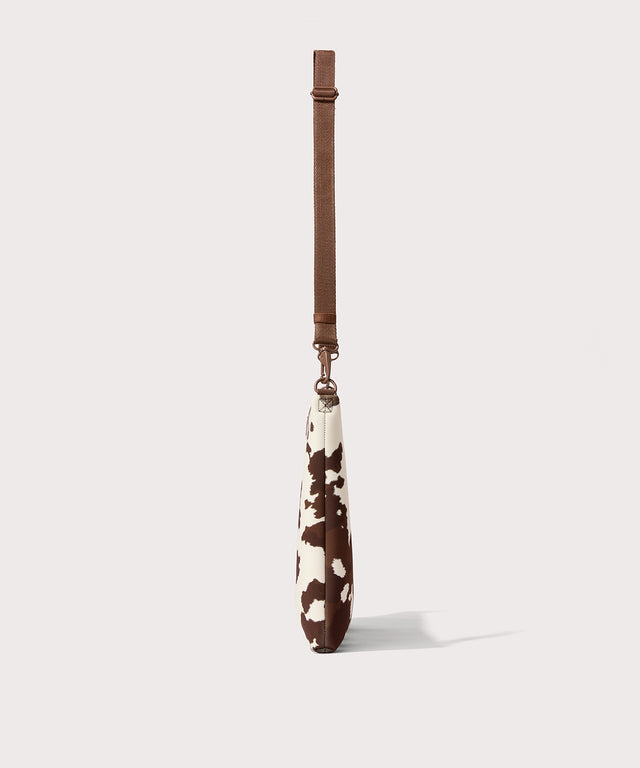 16 inch laptop shoulder bag in a cow print seen from the side view. 
