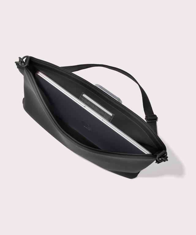 16 inch laptop shoulder bag in a black seen from the top down view showing interior.
