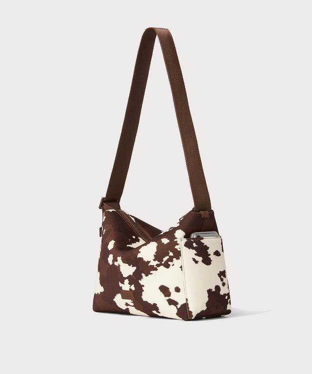 Shoulder bag in a cow print seen from the angle view. 