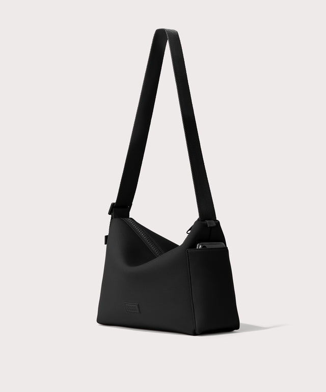 Shoulder bag in a black seen from the angle view showing phone pocket.
