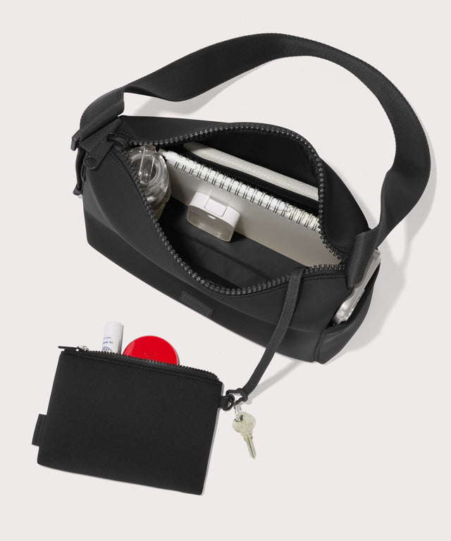 Shoulder bag in a black seen from the top down view showing interior mesh pouch.
