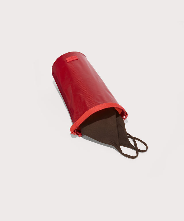 Dagne Dover Rae Roll-Top Dry Bag in a fiery, saturated red leaning toward orange on its side, unrolled, revealing the wipeable interior.