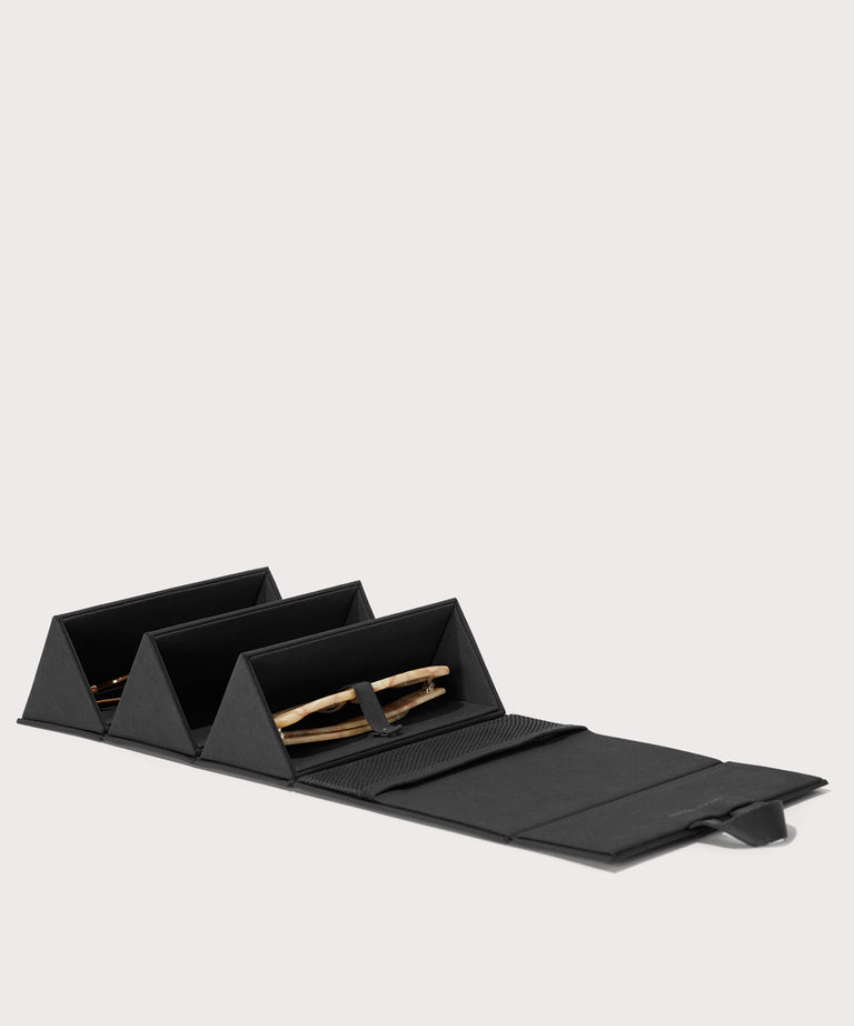 Dagne Dover Remi foldable glasses holder in black, unfolded and containing sunglasses.
