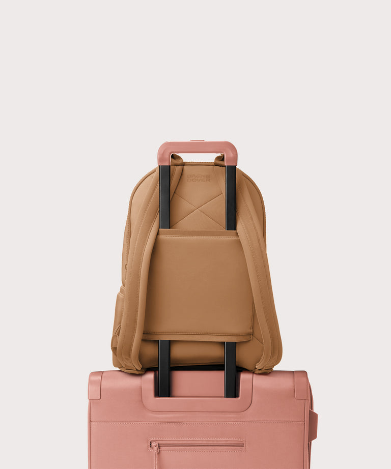 Dagne Dover large Dakota Neoprene Backpack in camel strapped to luggage with the neoprene luggage-handle sleeve.
