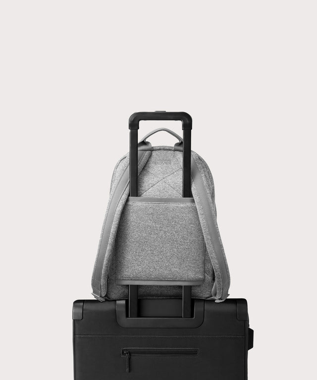 Dagne Dover medium Dakota Neoprene Backpack in grey strapped to luggage with the neoprene luggage-handle sleeve.
