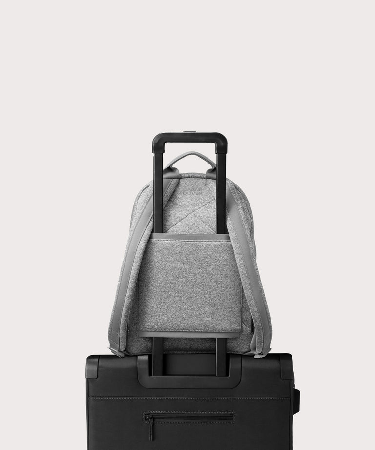 Dagne Dover medium Dakota Neoprene Backpack in grey strapped to luggage with the neoprene luggage-handle sleeve.
