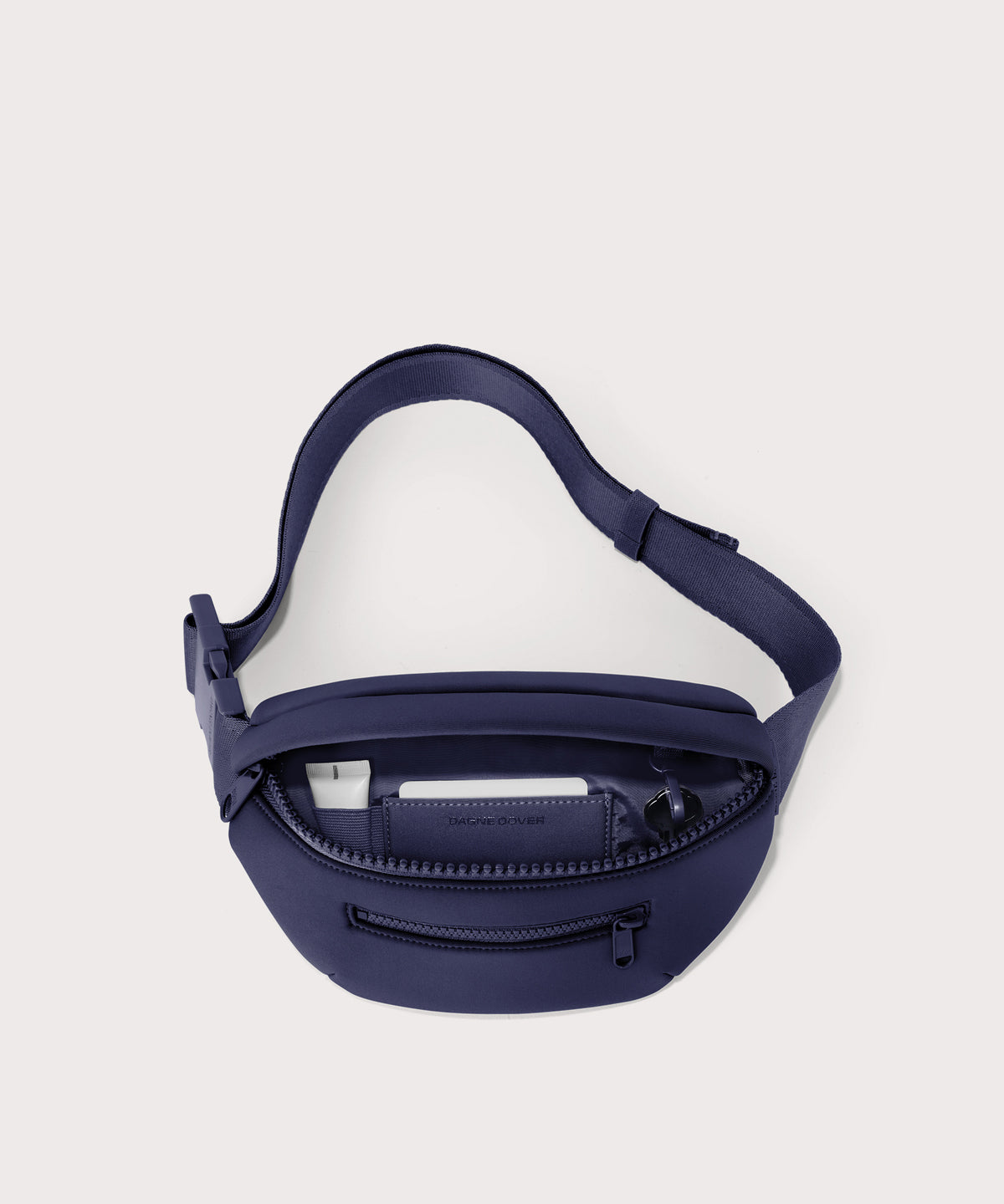 Dagne Dover Ace Fanny Pack in  dark blue  unzipped, exposing the interior pockets
