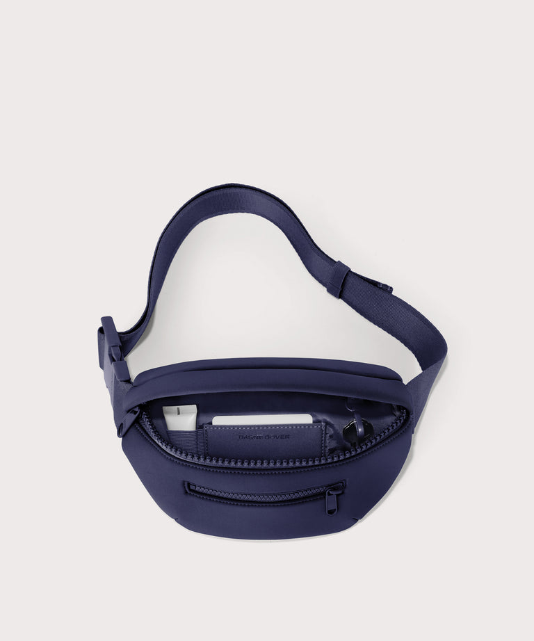 Dagne Dover Ace Fanny Pack in  dark blue  unzipped, exposing the interior pockets

