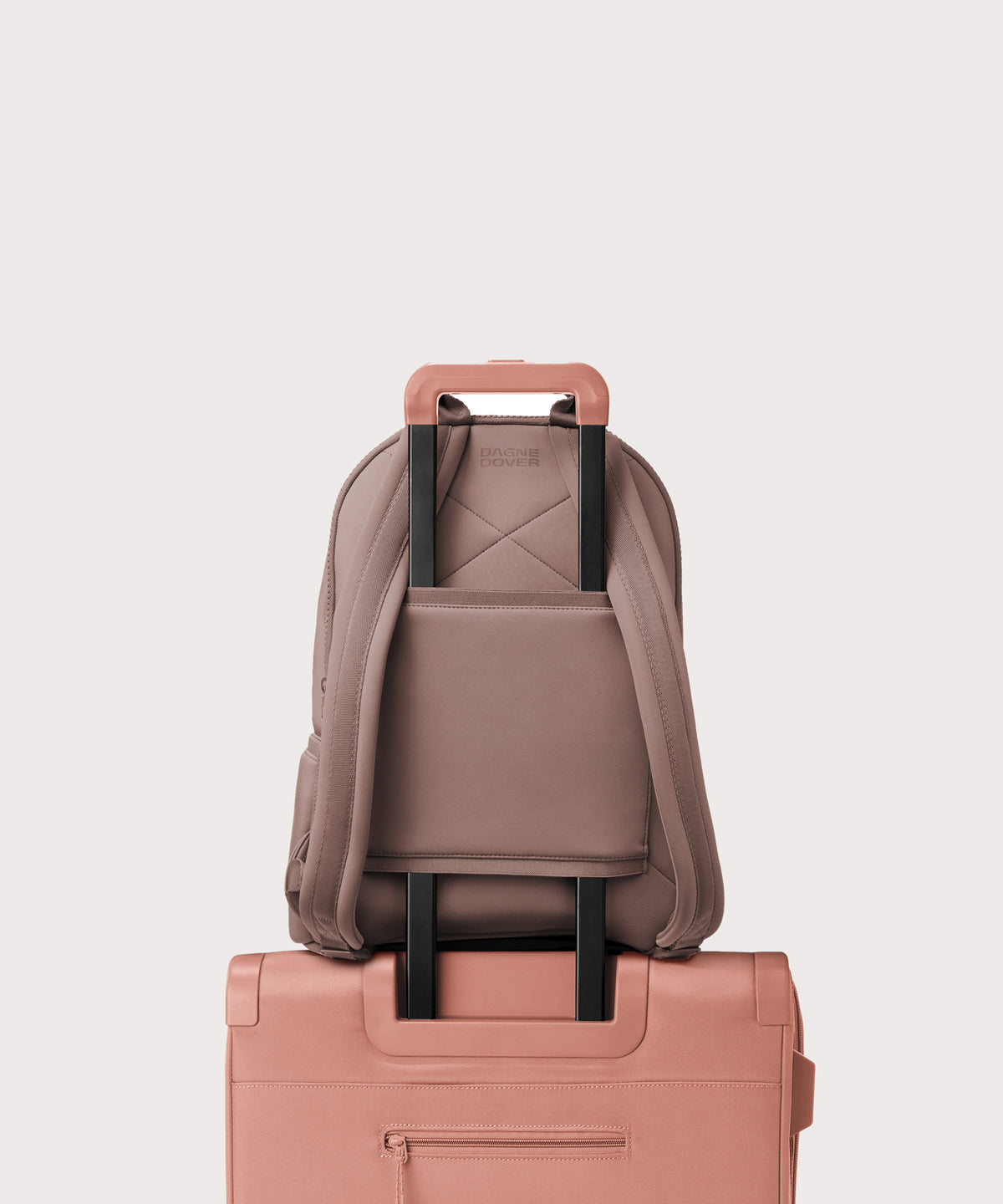 Dagne Dover large Dakota Neoprene Backpack in pink strapped to luggage with the neoprene luggage-handle sleeve.
