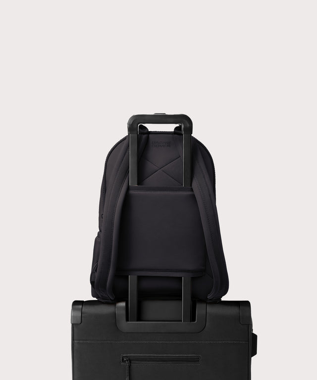 Dagne Dover large Dakota Neoprene Backpack in black strapped to luggage with the neoprene luggage-handle sleeve.
