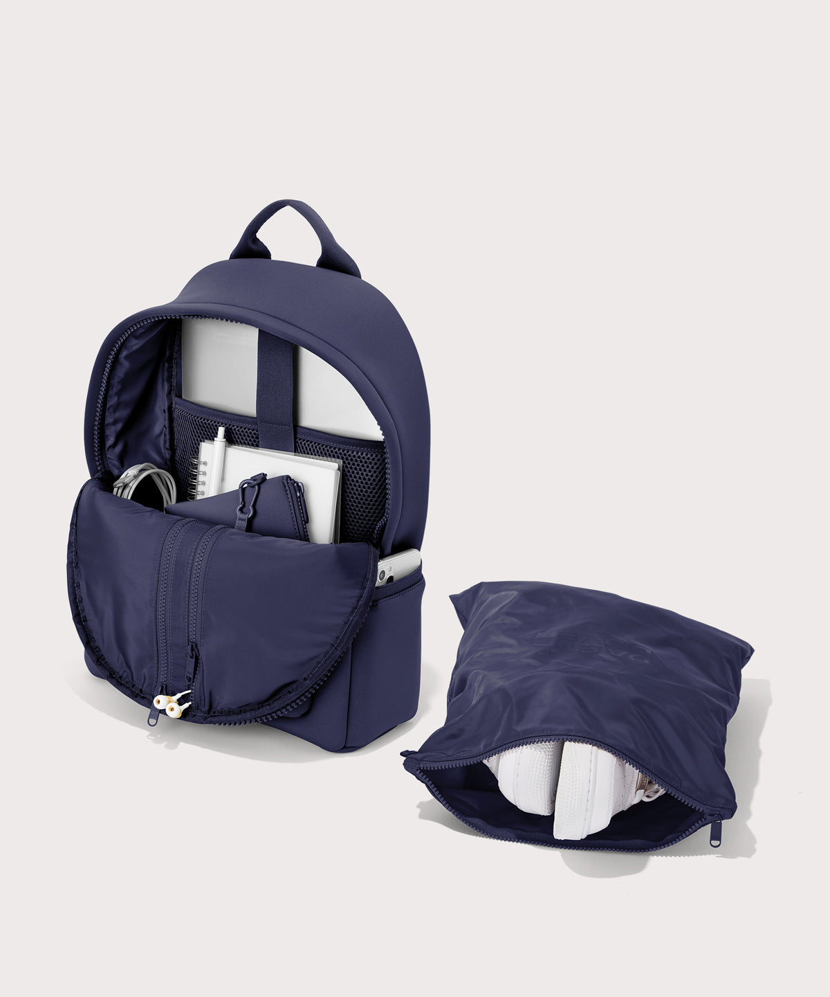 Dagne Dover medium Dakota Neoprene Backpack in dark blue unzipped, showing the interior pockets and shoe bag.

