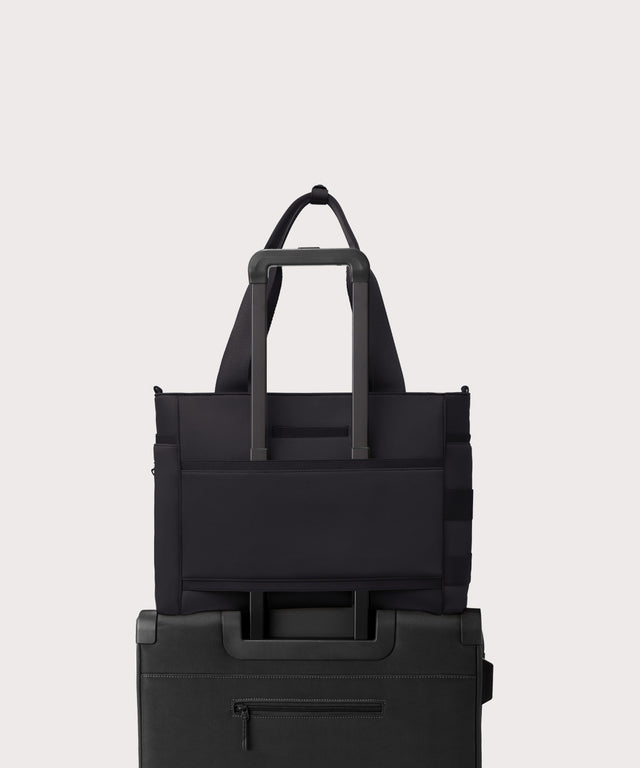 Dagne Dover large Wade Diaper Tote in black with the neoprene luggage sleeve attached to a suitcase handle.

