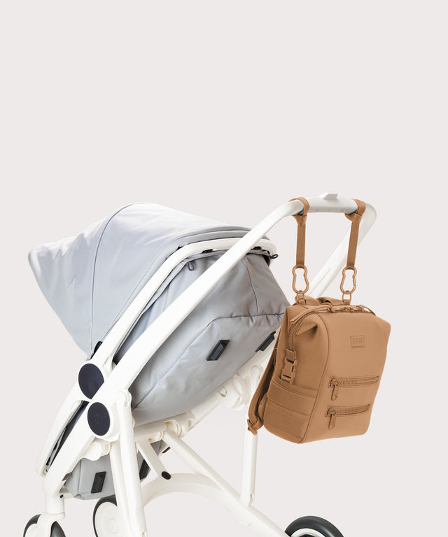 Dagne Dover small Indi Diaper Backpack in camel brown attached to a stroller.
