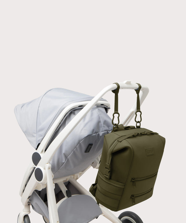 Dagne Dover Large Indi Diaper Backpack in dark moss attached to a stroller.
