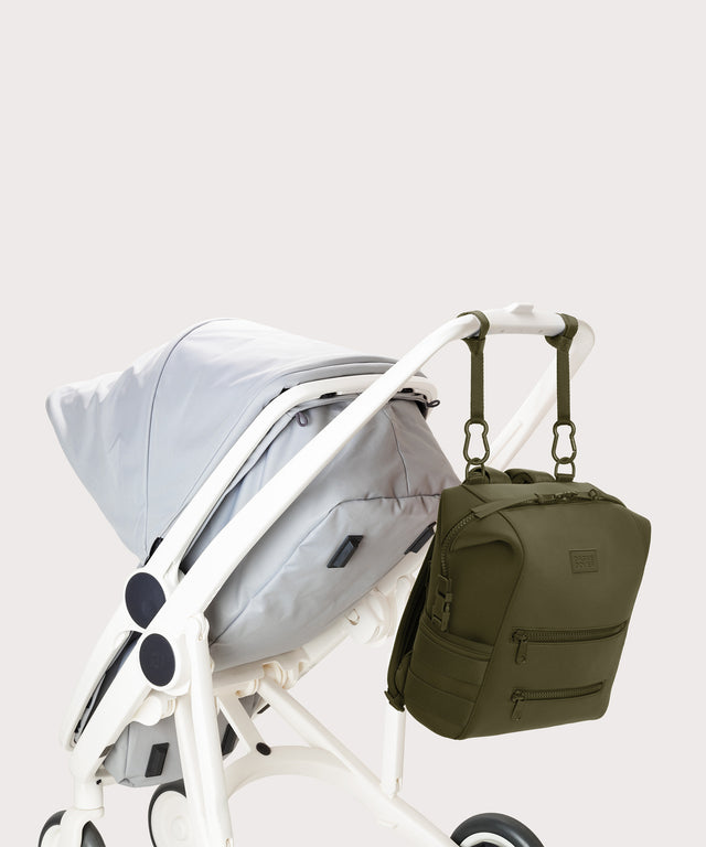Dagne Dover medium Indi Diaper Backpack in dark moss attached to a stroller.
