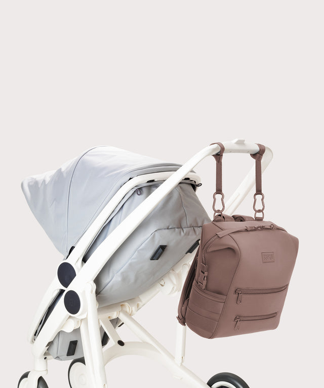 Dagne Dover medium Indi Diaper Backpack in pink attached to a stroller.
