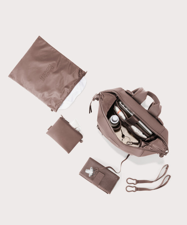 Dagne Dover medium Indi Diaper Backpack in pink showing it's water resistant bag, interior pockets, and changing mat.