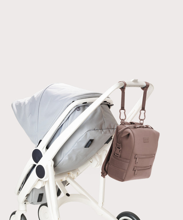 Dagne Dover small Indi Diaper Backpack in pink attached to a stroller.
