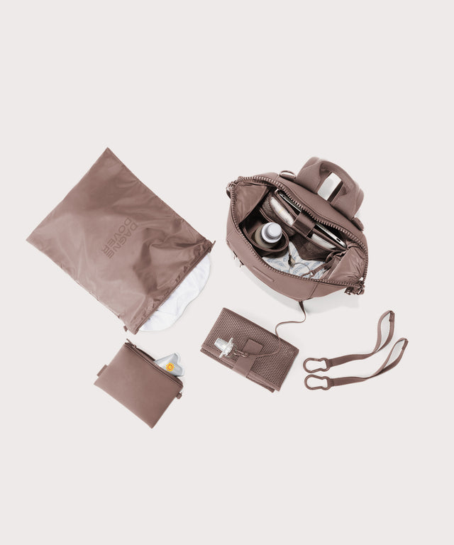 Dagne Dover small Indi Diaper Backpack in pink showing it's water resistant bag, interior pockets, and changing mat.