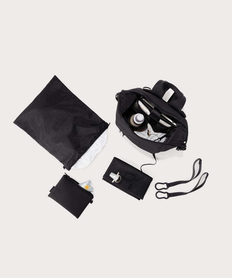 Dagne Dover small Indi Diaper Backpack in black showing it's water resistant bag, interior pockets, and changing mat.