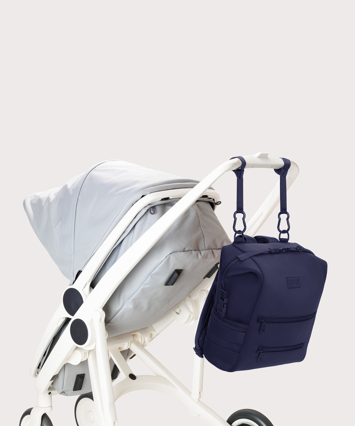Dagne Dover medium Indi Diaper Backpack in dark blue attached to a stroller.
