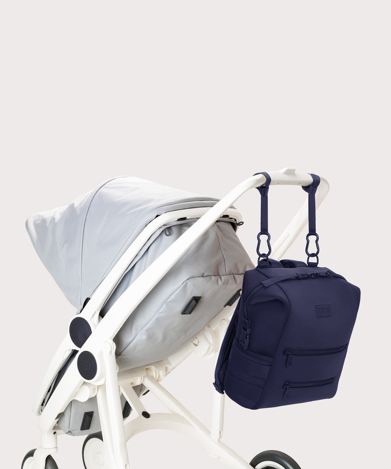 Dagne Dover medium Indi Diaper Backpack in dark blue attached to a stroller.
