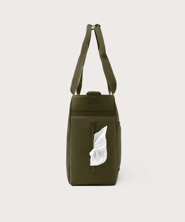 Dagne Dover large Wade Diaper Tote in dark green seen from the side, with a wet wipe poking out of the slip pocket.
