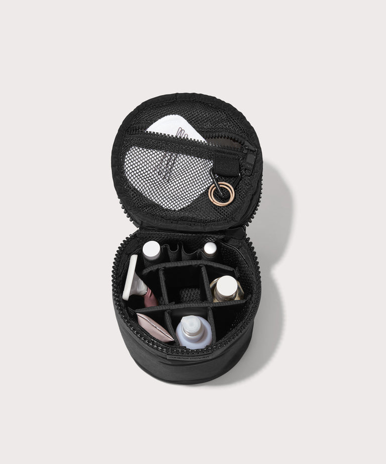 Dagne Dover large Mila Toiletry Pouch in black unzipped filled with toiletry products.
