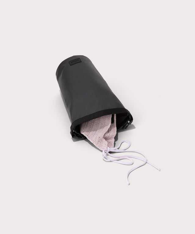 Dagne Dover Rae Roll-Top Dry Bag in black on its side, unrolled, revealing the wipeable interior.