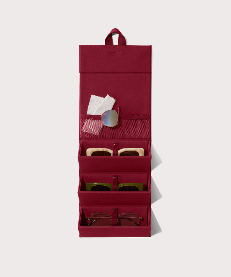 Dagne Dover Remi foldable glasses holder in spice red hung up and holding glasses.
