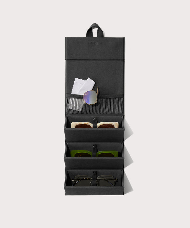 Dagne Dover Remi foldable glasses holder in black hung up and holding glasses.
