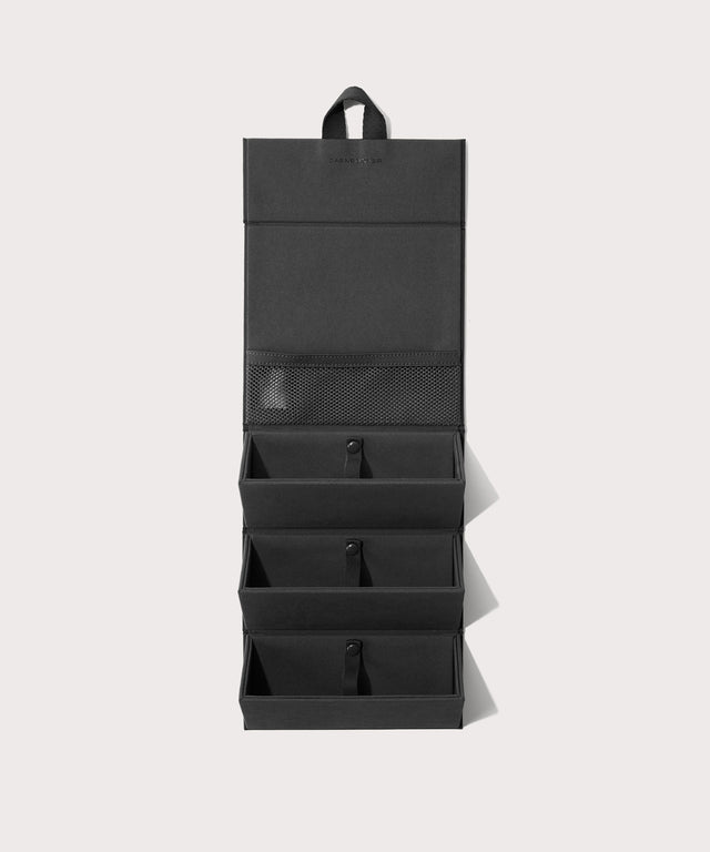 Dagne Dover Remi foldable glasses holder in black hung up.
