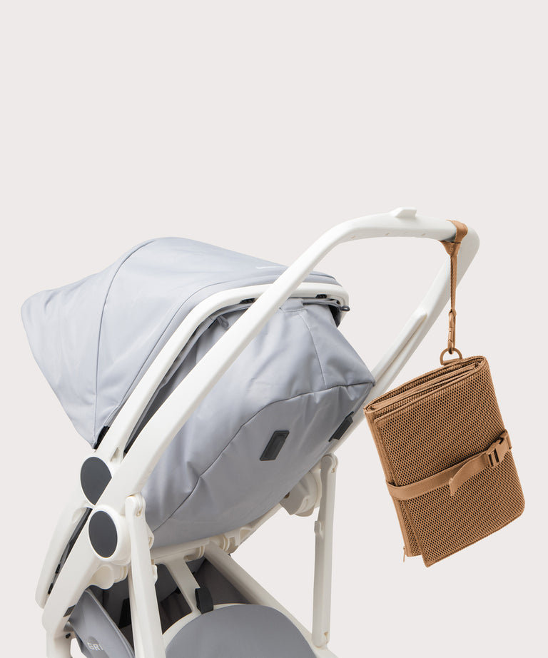 Dagne Dover Joey Changing Kit in camel brown strapped to the handle of a stroller.
