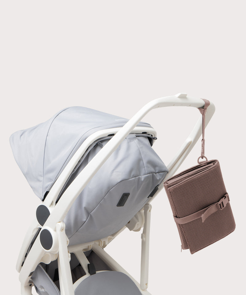 Dagne Dover Joey Changing Kit in pink strapped to the handle of a stroller.
